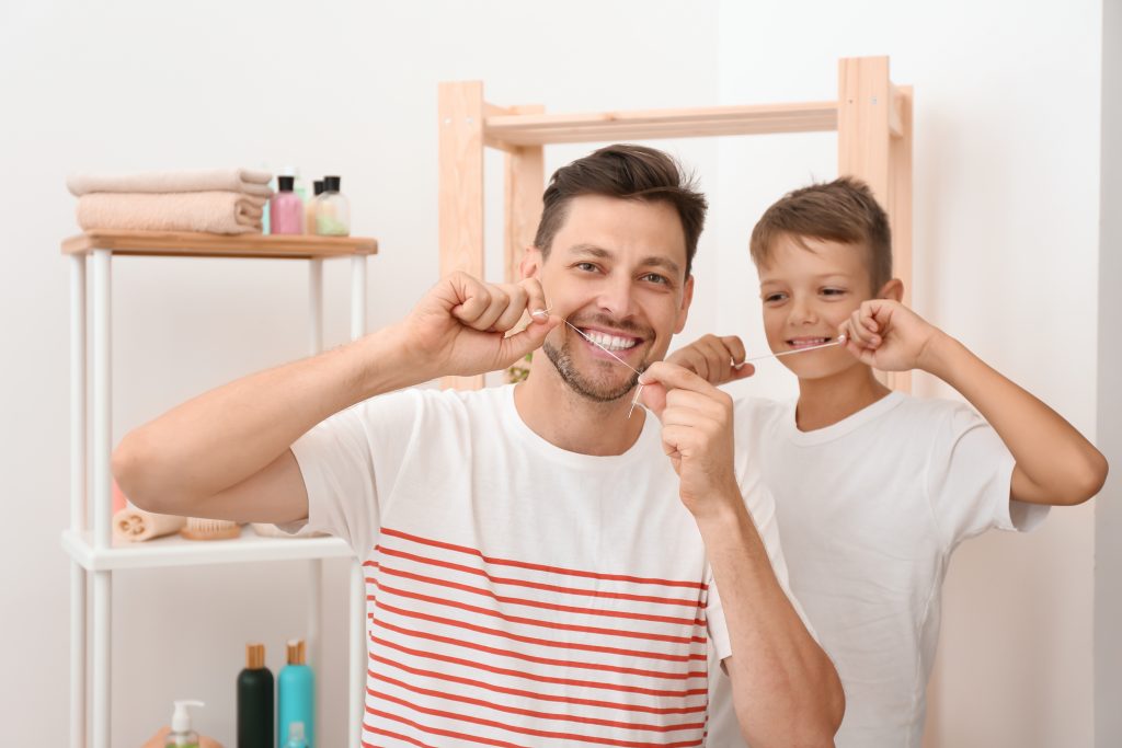 Father and Son Flossing Their Teeth